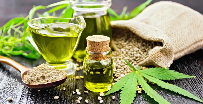 Hanföl ist in einem Fläschchen mit Samen und Pulver daneben.