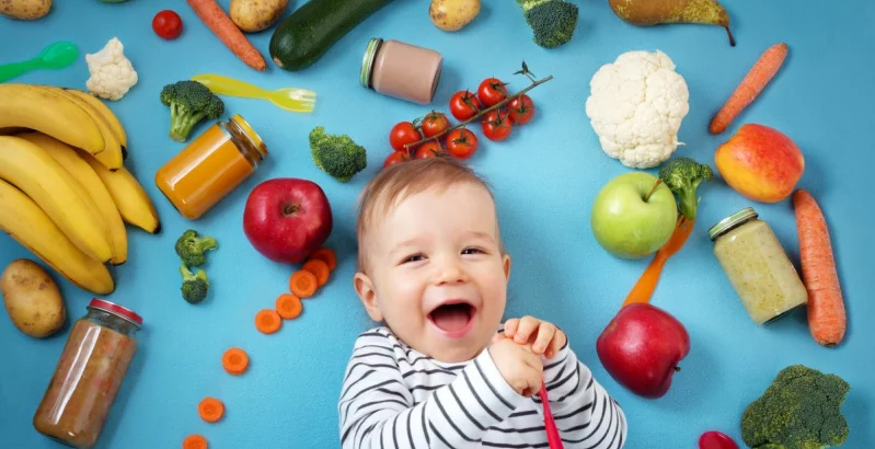 Kind von Gemüse und Früchten umgeben.