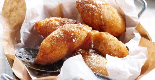 Luftige, frittierte Teigbällchen mit Banane am Teller