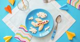 Baby-Frühstück auf blauem Teller mit einer Banane in Flugzeugform