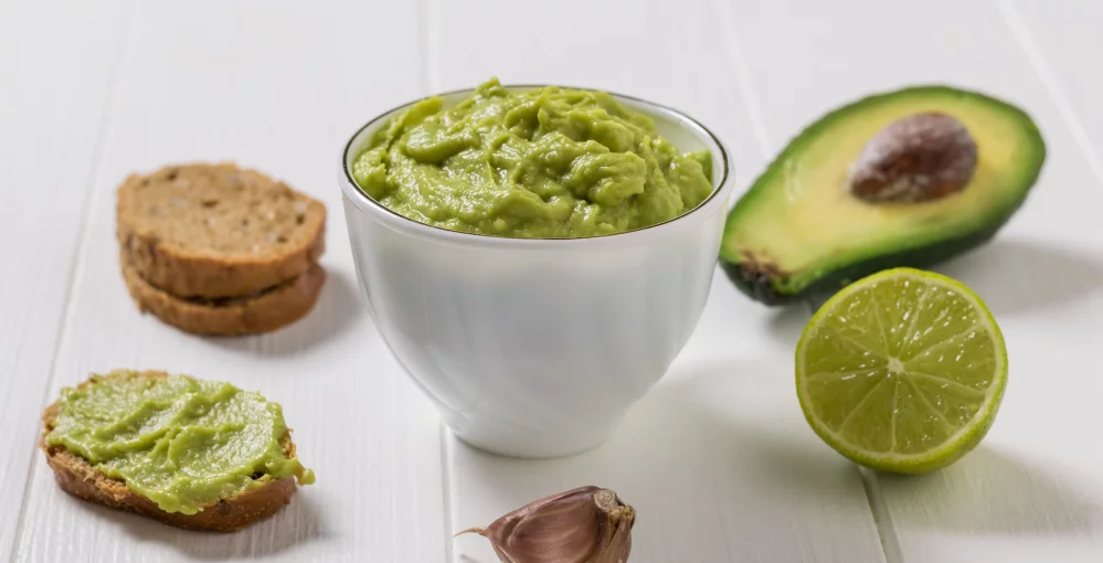 Guacamole – Avocado-Aufstrich Auf dem Tisch eine Schale Guacamole mit Avocado und Brot