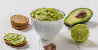 Auf dem Tisch eine Schale Guacamole mit Avocado und Brot