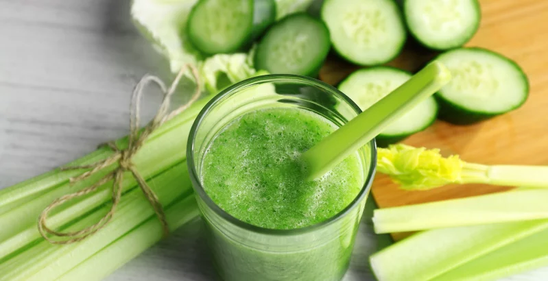 Selleriesaft in einer Tasse mit geschnittenem Gemüse und Sellerie